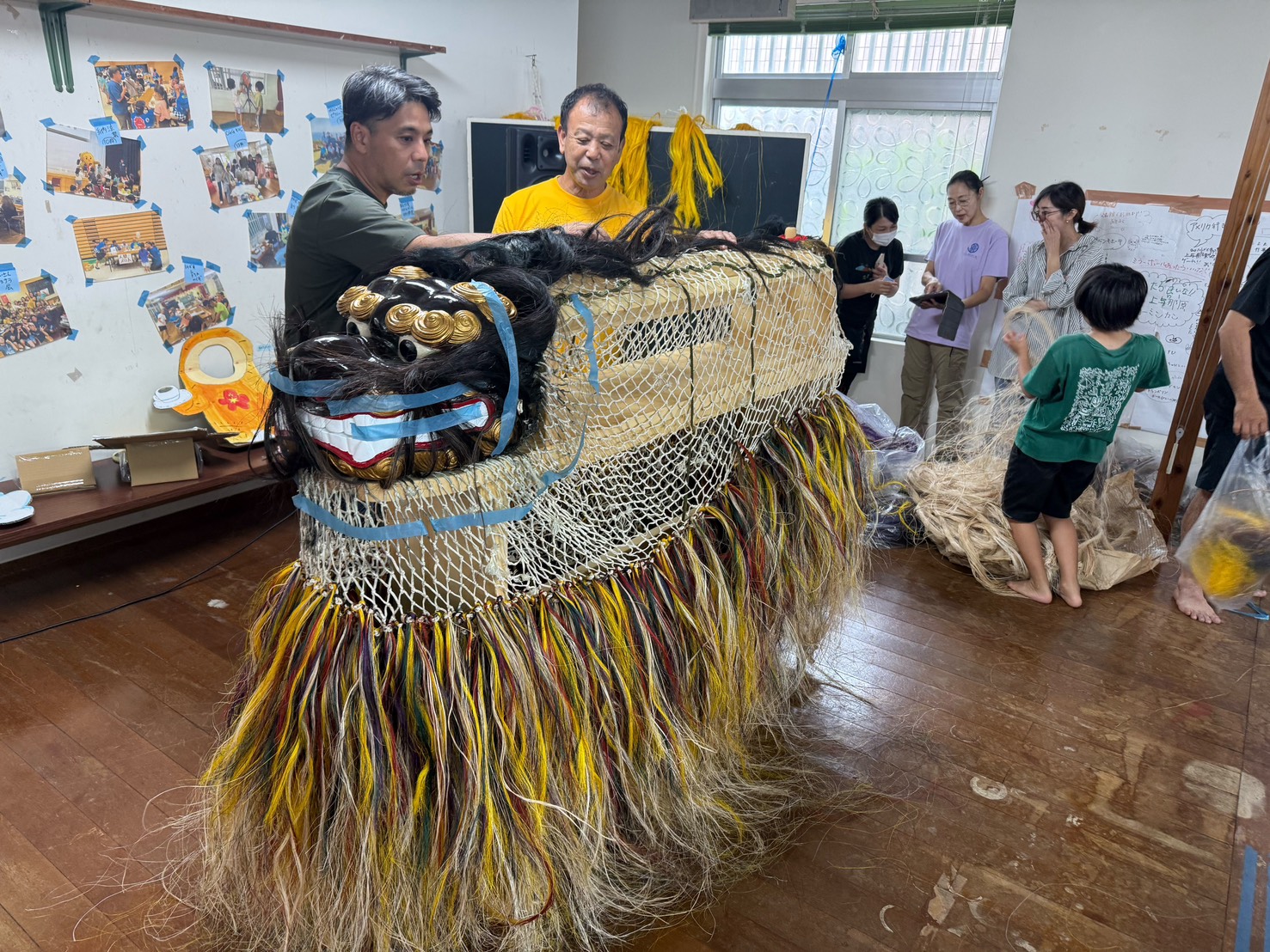 上与那原の獅子舞の修繕に携わる新垣信人と地域の皆さん